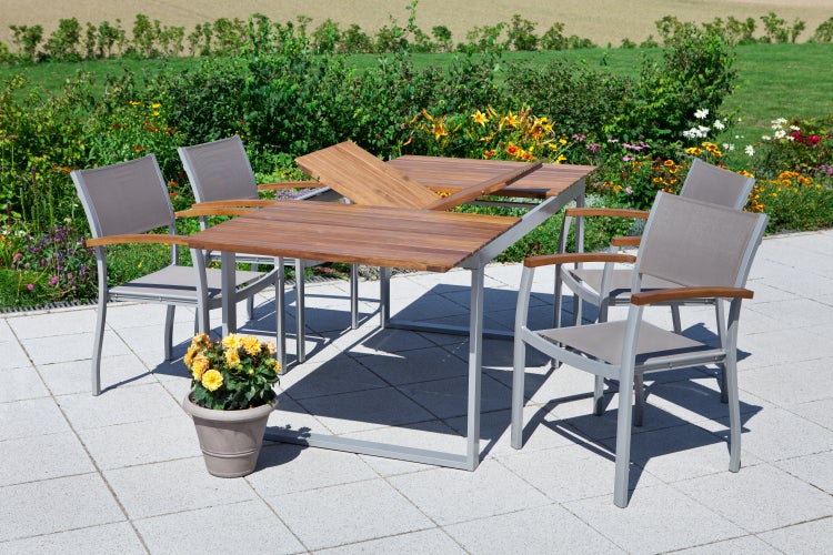 Gartenszene mit Ausziehtisch und vier Stühlen auf einer Terrasse