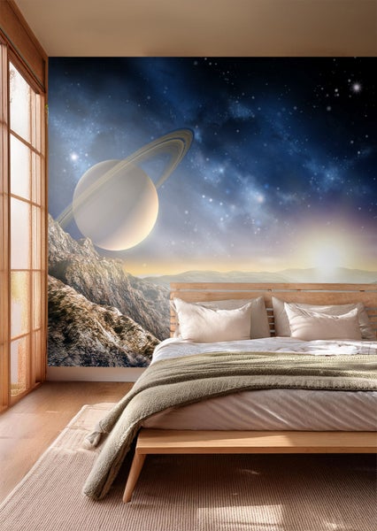 Schlafzimmer mit Fototapete, die einen Planeten mit Ringen über einer Berglandschaft zeigt