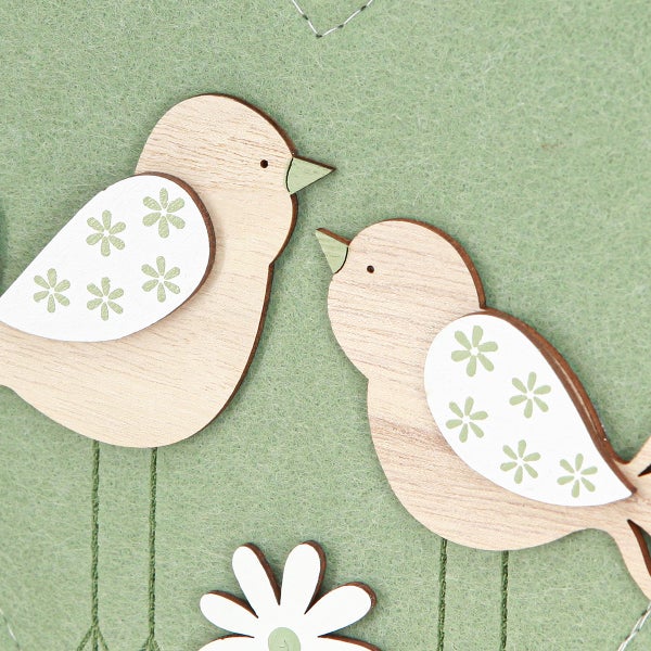 Dekoration mit Holzvögeln und Blumen auf Filz