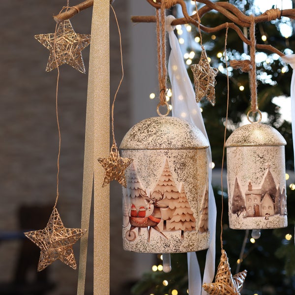 Weihnachtsdekoration mit zwei hängenden Glocken aus Metall und Drahtsternen an einem Ast, festliche Dekoration für das Zuhause.