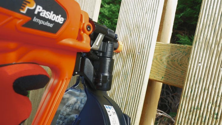 Ein Paslode Impulse Nagler wird verwendet um Holzlatten an einem Holzzaun zu befestigen.