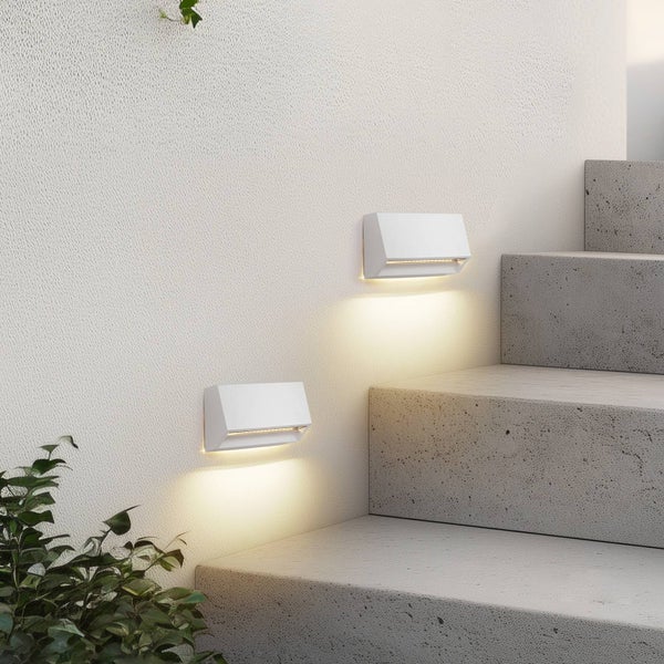 Zwei weiße LED-Außenwandleuchten beleuchten eine graue Betontreppe an einer weißen strukturierten Wand.