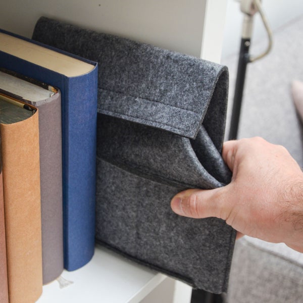 Hand platziert Filz Aufbewahrungstasche mit Klettverschluss in ein Regal neben Büchern