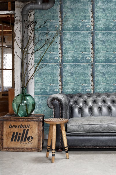 Szene mit Sofa, Hocker, Holzkiste und Wandpaneelen im Industriedesign