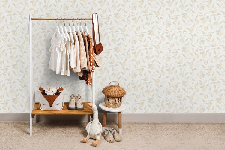 Kinderzimmer mit Kleiderständer, Kleidung, Spielzeug und Tapete mit Zitronenmuster