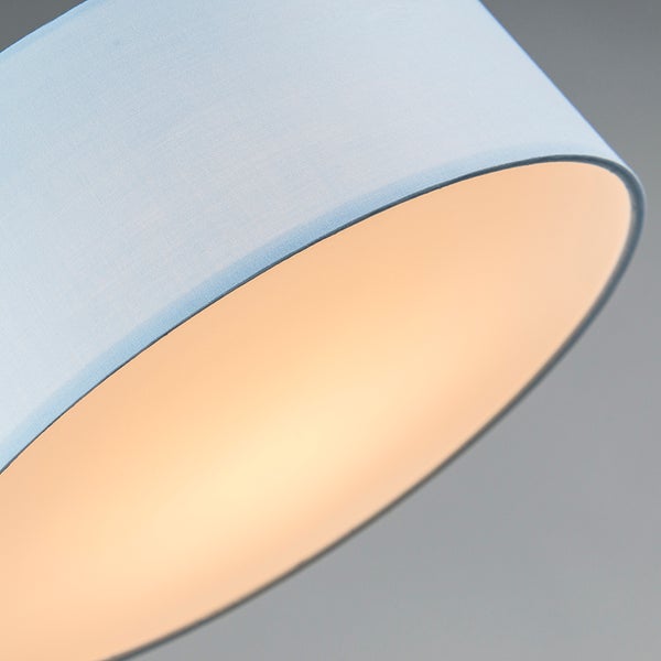 Nahaufnahme eines runden Lampenschirms aus hellblauem Textil mit warm leuchtender Innenseite.