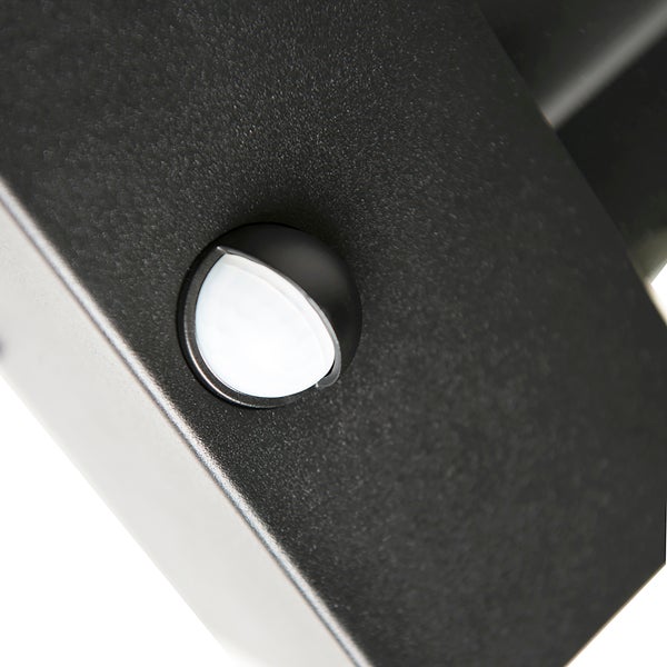 Detailaufnahme eines Bewegungsmelders an einer schwarzen Außenleuchte.