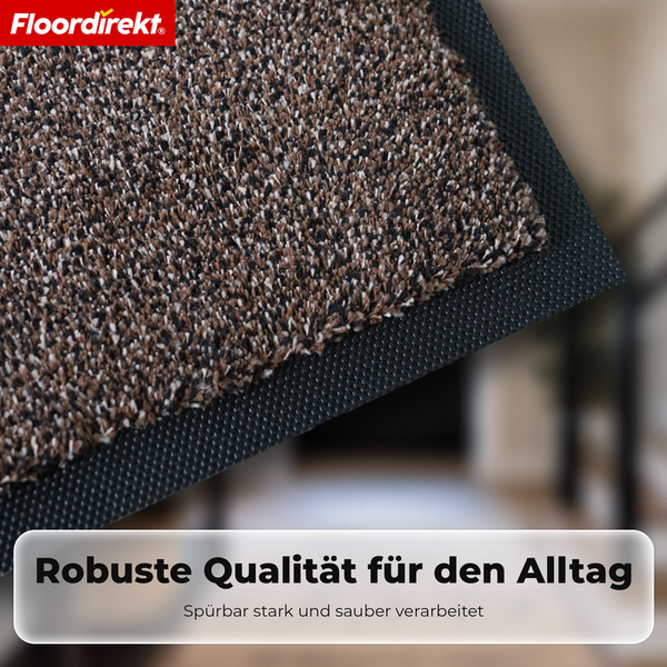 Floordirekt Logo. Detailaufnahme einer robusten Fußmatte mit melierter Textur und genopptem Gummirand.