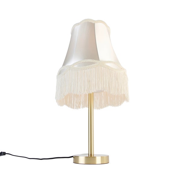 Tischleuchte im Vintage-Stil mit cremefarbenem Stoffschirm mit Fransen und goldfarbenem Metallfuß.