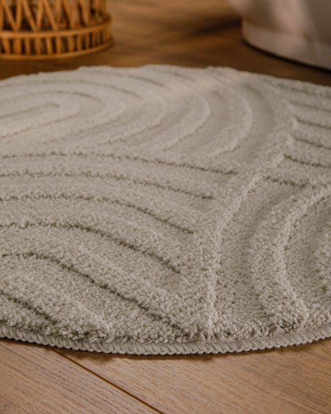 Runder Badeteppich mit reliefartiger Oberflächenstruktur und wellenförmigem Muster.