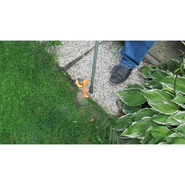 Unkrautbrenner im Einsatz auf einer gepflasterten Fläche neben Rasen und Pflanzen.