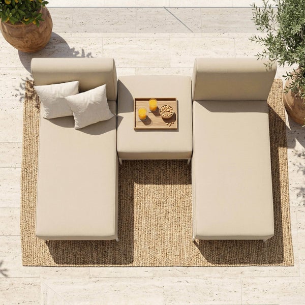 Moderne Gartenlounge aus der Vogelperspektive mit zwei beigen Daybeds, einem Hocker und einem Outdoorteppich auf einer Steinterrasse.