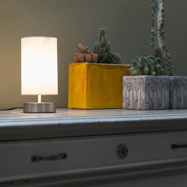 Dekorative Tischleuchte neben Kakteen auf einem Tisch