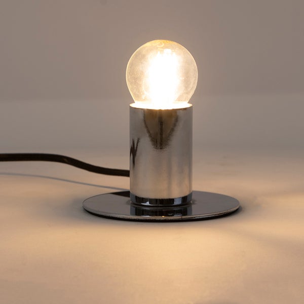 Tischleuchte mit verchromtem Sockel und leuchtender Filament LED Birne.