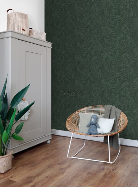 Kinderzimmer mit Tapete mit Blattmuster, Kleiderschrank und Rattansessel.