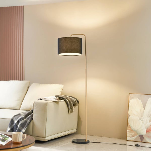 Moderne Stehlampe mit messingfarbenem Gestell, schwarzem Textilschirm und Marmorfuß neben einem hellen Sofa im Wohnzimmer.