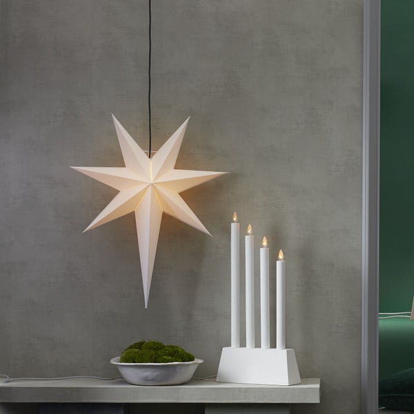 Dekorative Szene mit einem Papierstern, Adventsleuchter und einer Schale mit Moos auf einem Tisch.