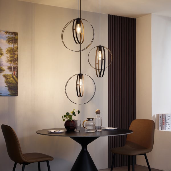 Moderne Pendelleuchte mit drei runden Metallrahmen über einem runden Esstisch mit zwei Stühlen in einem eleganten Wohnbereich.