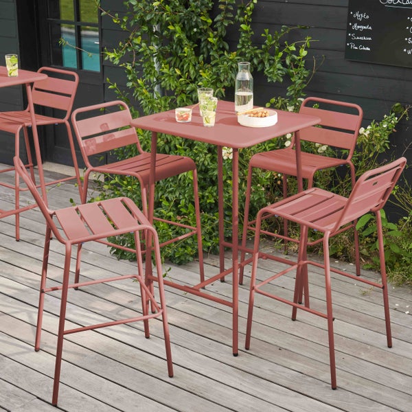 Set aus Metall-Stehtisch und vier Barhockern auf einer Holzterrasse mit Pflanzen.