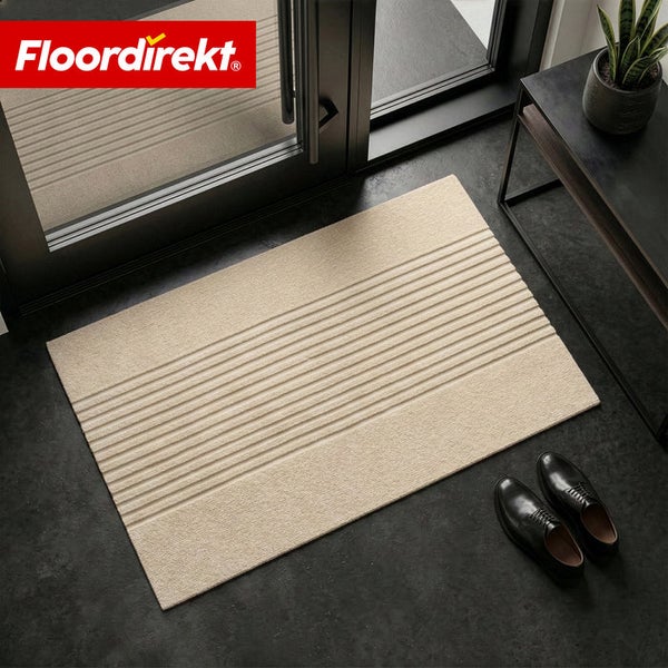 Floordirekt Logo. Beige rechteckige Fußmatte mit Streifenmuster im Eingangsbereich vor einer Tür neben Schuhen.
