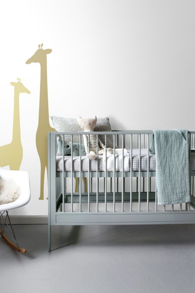 Zimmer mit Kinderbett, Kissen und Giraffen Wandtattoo