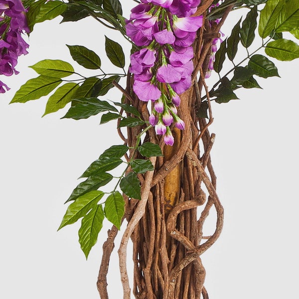 Detailansicht einer Kunstpflanze mit einem verschlungenen Stamm aus echtem Holz in einem dunklen Topf.