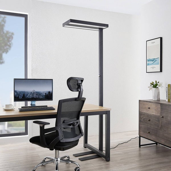 Moderner Büro-Arbeitsplatz mit schwarzer LED-Stehleuchte, Holzschreibtisch, ergonomischem Bürostuhl und Monitor in hellem Raum.
