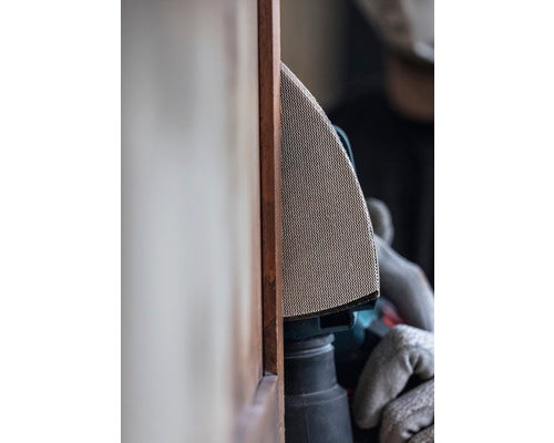 Eine Person schleift Holz mit einem Elektrowerkzeug.