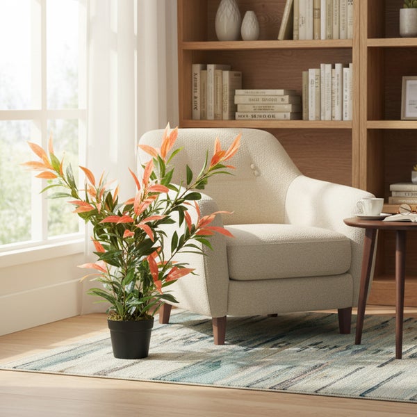 Helle Leseecke mit Sessel, Bücherregal und Kunstpflanze als Dekoration.