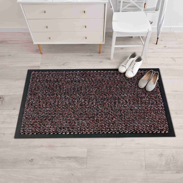 Schmutzfangmatte mit Schuhpaar, Kommode und Stuhl in einem Eingangsbereich