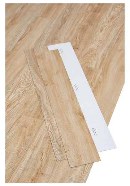 Selbstklebende Vinylplanken in Holzoptik mit Verlegepfeilen auf der Rückseite.