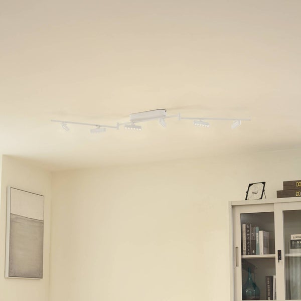Weiße Deckenleuchte mit mehreren rechteckigen Strahlern an beweglichen Armen in einem hellen Raum mit Regal und Bild.