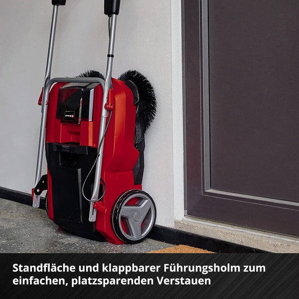 Einhell Kehrmaschine mit klappbarem Führungsholm und Standfläche für platzsparende Aufbewahrung an einer Wand.