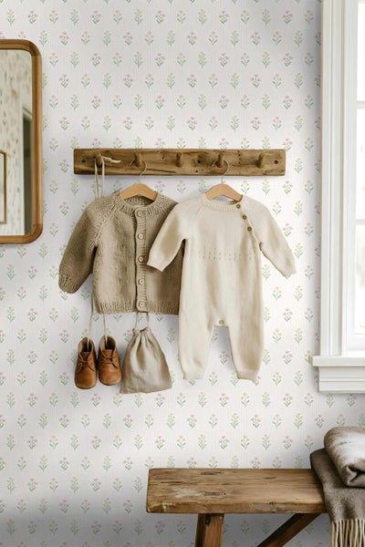 Vliestapete mit kleinen rosa und gelben Blumen auf gestreiftem weißem Hintergrund in einem Kinderzimmer mit Holzgarderobe und Strickkleidung.