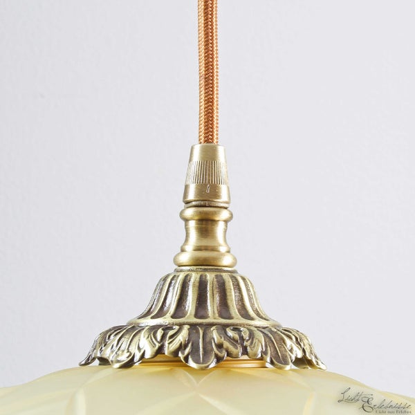 Detailaufnahme einer Pendelleuchte mit Textilkabel und verzierter Lampenaufhängung