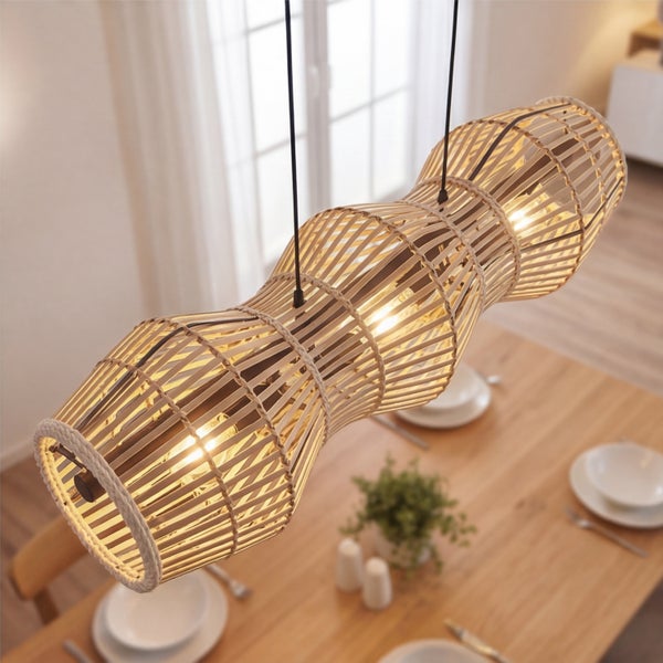 Dreiflammige Pendelleuchte aus Bambusgeflecht in Natur-Optik, hängend über einem gedeckten Esstisch aus Holz in einem hellen Raum.