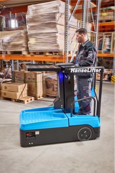 HanseLifter Elektro-Kommissionierer in Betrieb in einem Lager mit Regalen und verpackten Waren.