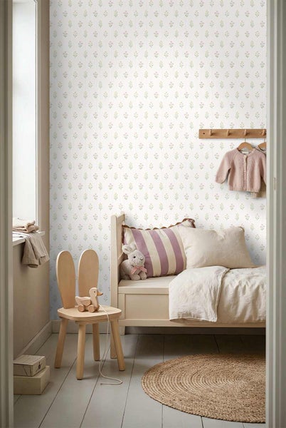 Helles Kinderzimmer mit floral gemusterter Tapete, einem Holzbett, einem Stuhl in Hasenohren-Optik und einem runden Teppich.
