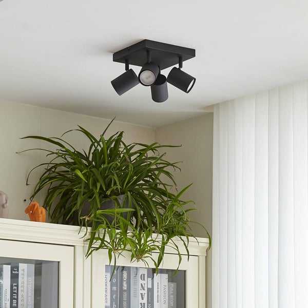 Schwarze Deckenleuchte mit drei Strahlern in einem hellen Raum.