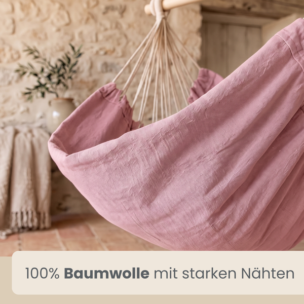 Hängesessel aus 100 Prozent Baumwolle mit stabilen Nähten an einem Holzstab in einem Raum mit Natursteinwand.