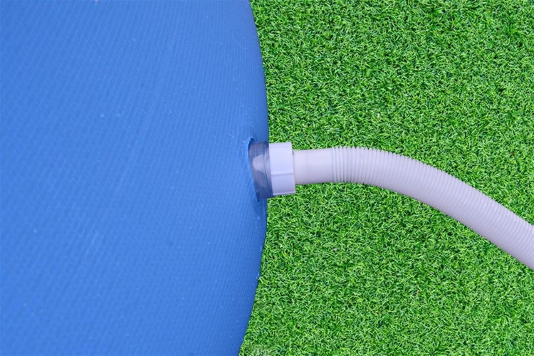Detailaufnahme eines Poolanschlusses mit Schlauch auf Rasen