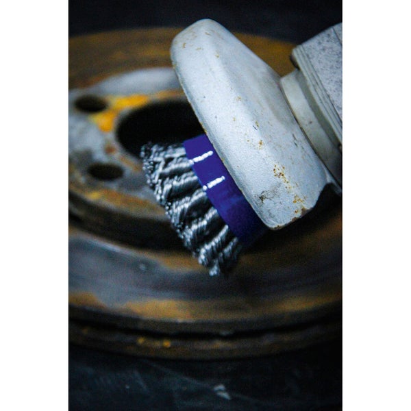 Drahtbürste reinigt eine Metalloberfläche