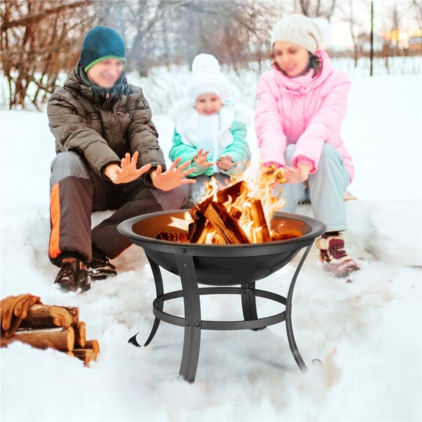 Familie wärmt sich an einer Feuerschale im Schnee.