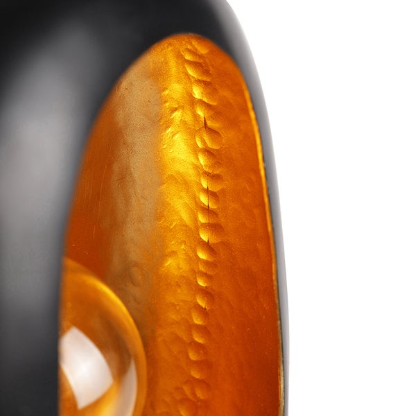 Detailaufnahme einer schwarzen und goldenen Lampe, die Licht ausstrahlt.