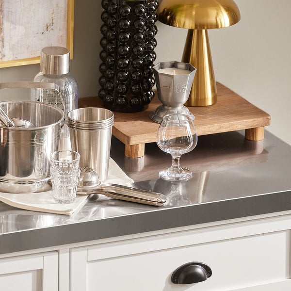 Dekorative Anordnung mit Getränkezubehör, Glaswaren und dekorativen Elementen auf einer Arbeitsfläche.