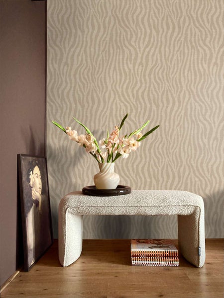 Wohnzimmer mit Vliestapete mit Wellenmuster, einer Bank aus Boucle Stoff und einer Vase mit Blumen auf einem Holzboden.