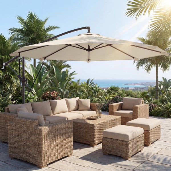 Moderne Garten-Lounge-Gruppe aus Geflecht mit beigen Polstern, Couchtisch, Sesseln, Hocker und großem Ampelschirm auf einer sonnigen Terrasse.