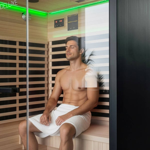 Mann entspannt in einer modernen Infrarotsauna aus Holz mit Glastür und indirekter LED Beleuchtung.