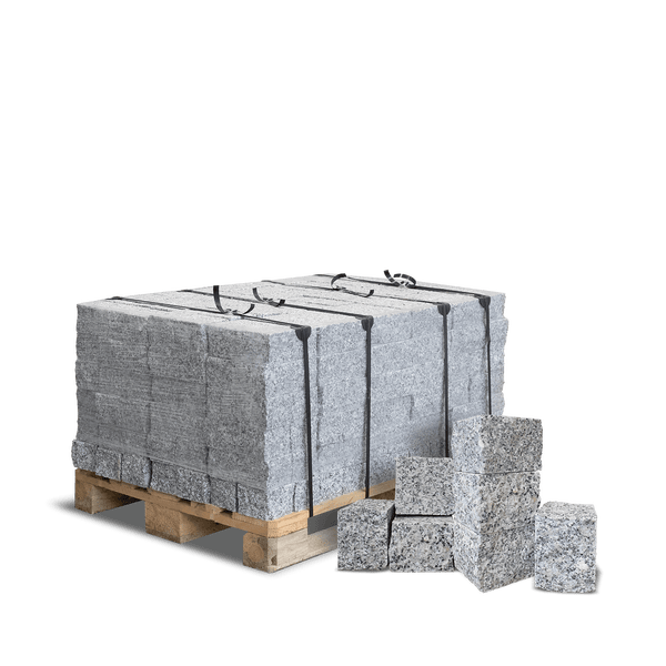Granitpflastersteine auf einer Holzpalette, gesichert mit Umreifungsbändern, mit einzelnen Natursteinen im Vordergrund.