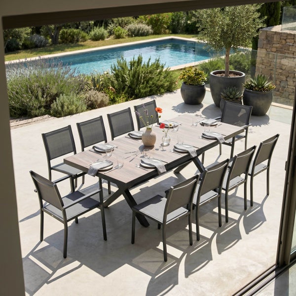 Garten-Essgruppe auf einer Terrasse mit rechteckigem Tisch in Holzoptik und zehn Metallstühlen mit Netzbespannung, neben einem Pool und Pflanzen.